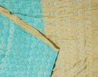 May include: A turquoise and gold saree with a floral pattern. The saree has a gold border and is decorated with sequins.