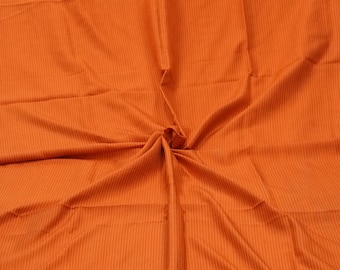 Op de afbeelding: Oranje gestreept stof met een subtiele glans. De stof is in het midden gevouwen, waardoor een stervormig patroon ontstaat.