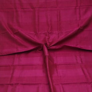 Peut inclure: Gros plan sur un tissu magenta vif avec de fines rayures horizontales. Le tissu est plié au centre, créant des plis et des ombres douces. Le matériau a un aspect lisse et brillant, suggérant un textile de haute qualité.