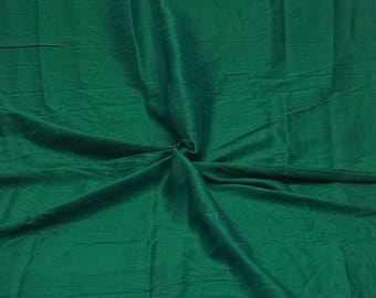 Op de afbeelding: Een effen donkergroene stof met een matte afwerking en een zichtbare weefstructuur. Het materiaal is gedrapeerd vanuit een centraal punt, wat zorgt voor zachte, uitstralende plooien en natuurlijke kreukels over het gehele oppervlak van het textiel.