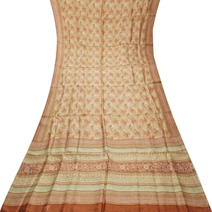 Puede incluir: Un sari de seda beige con un estampado floral marrón y un borde con un diseño repetido de verde, marrón y blanco.