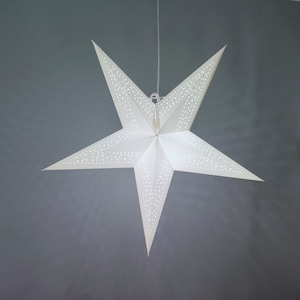 May include: A white paper star lantern with a delicate, intricate design. The star is hanging from a white string and has a white background.