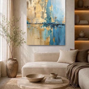 May include: A rectangular canvas wall art piece featuring an abstract composition of vertical brushstrokes in shades of gold, light blue, and white, with a dark horizontal line separating the upper and lower sections of the textured painting.
