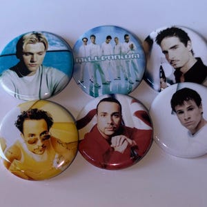 Op de afbeelding: Set van zes ronde pinback-knoppen met afbeeldingen van een boyband. Elke knop toont een ander lid, met verschillende poses en achtergronden. De knoppen zijn glanzend en hebben een klassiek pin-ontwerp.