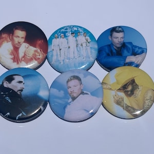 Könnte beinhalten: Eine Sammlung von sechs runden Ansteckbuttons mit Bildern männlicher Prominenter. Die Buttons zeigen verschiedene Porträts und Gruppenaufnahmen in verschiedenen Farben, darunter Blau, Gelb und Weiß. Die Buttons sind glänzend und haben eine reflektierende Oberfläche.