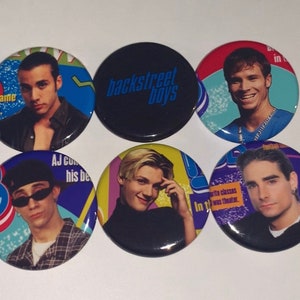 Könnte beinhalten: Sechs runde Knöpfe mit Bildern der Mitglieder der Backstreet Boys. Die Knöpfe sind schwarz mit einem silbernen Rand. Die Knöpfe zeigen den Bandnamen "Backstreet Boys" in blauer Schrift. Jeder Knopf zeigt ein anderes Bandmitglied mit einem bunten Hintergrund.