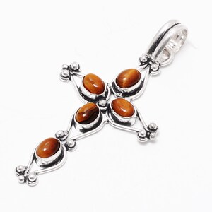 Peut inclure: Pendentif en argent en forme de croix avec cinq pierres en œil de tigre brun.