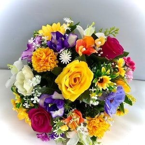 May include: A colorful artificial flower arrangement with yellow, red, purple, and white flowers. The arrangement is in a round shape and is perfect for a centerpiece or a decorative accent.