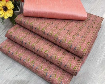 May include: A stack of pink fabric with a patterned design of vertical lines and small leaf-like shapes in green, blue, and white. A solid pink fabric square rests on top. The fabrics are likely for sewing or crafting.