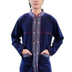 May include: A navy blue long-sleeved shirt with a mandarin collar and two front pockets. The shirt features embroidered floral detailing along the front, collar, and pockets. It has wooden buttons and red accent stitching.