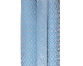 May include: A light blue skirt with a detailed pattern. The skirt features a repeating diamond design with a floral motif. A matching fabric accent is attached at the waist. The skirt is made of a shiny material.