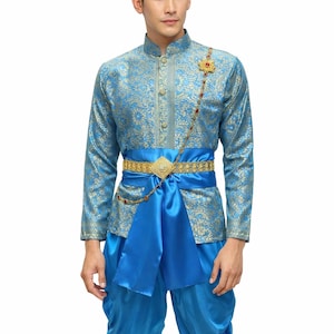 May include: A traditional Thai costume in shades of blue and gold. The outfit includes a long-sleeved shirt with intricate gold patterns, matching pants, and a gold belt with a decorative buckle. A jeweled brooch and chain add to the elegance.