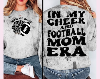 Op de afbeelding: Een wit sweatshirt met een verweerd, tie-dye-effect. De voorkant van het sweatshirt heeft de tekst "Mom of Both" met een cheerleading pompon en een voetbalafbeelding. De achterkant van het sweatshirt heeft de tekst "In My Cheer and Football Mom Era" in een retro-lettertype.