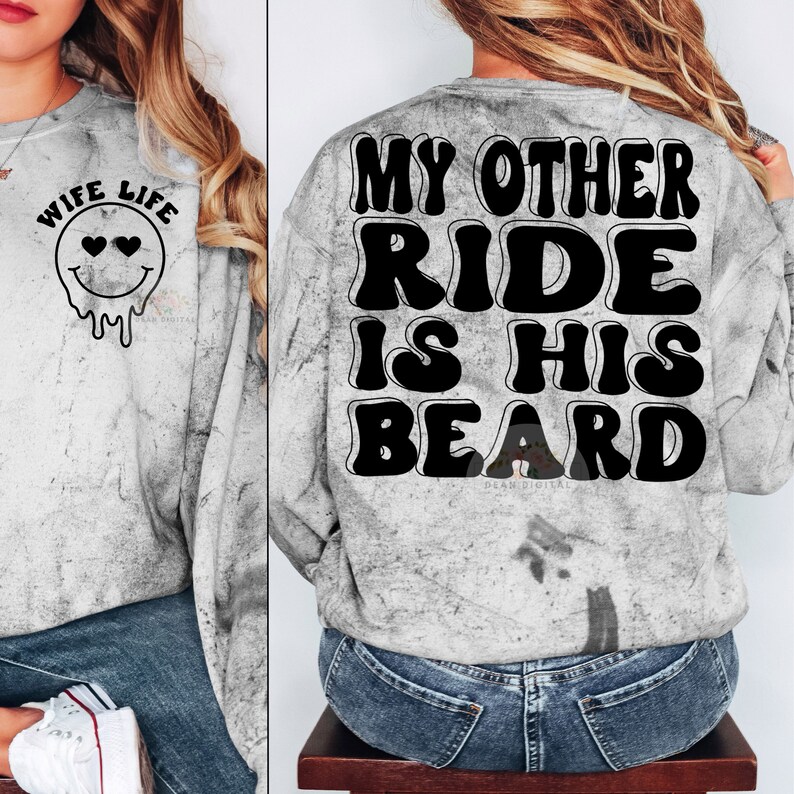 K&ouml;nnte beinhalten: Ein graues Sweatshirt mit einem Used-Look. Die Vorderseite des Sweatshirts tr&auml;gt den Text "Wife Life" mit einem tropfenden Smiley. Die R&uuml;ckseite des Sweatshirts tr&auml;gt den Text "My Other Ride Is His Beard" in einer Retro-Schrift.