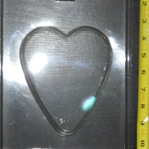 Puede incluir: Un molde de plástico negro para hacer chocolates o caramelos en forma de corazón. El molde tiene una sola cavidad en forma de corazón.