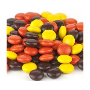 May include: A close-up of a pile of chocolate candies. The candies are in three colors: brown, yellow, and orange. The candies are round and have a smooth surface.