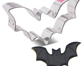 Könnte beinhalten: Ein silberner Fledermaus-Ausstecher aus Metall mit einem schwarzen Fledermaus-Keks auf weißem Hintergrund. Der Ausstecher trägt die Aufschrift "Made in USA".