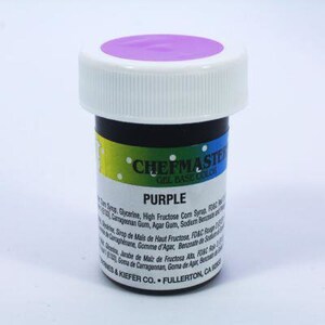 Peut inclure: Un petit pot de colorant alimentaire en gel violet de la marque "Chefmaster" avec le texte "Gel Base Color" imprimé sur l'étiquette. Le pot a un couvercle blanc et un bouchon violet.