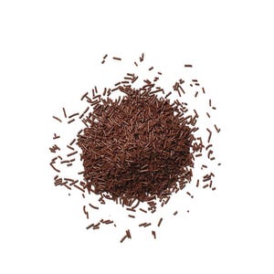 Puede incluir: Vista superior de un montón de virutas de chocolate marrón oscuro sobre un fondo blanco. Las virutas son pequeñas formas cilíndricas. La imagen muestra las virutas en el centro y dispersas.