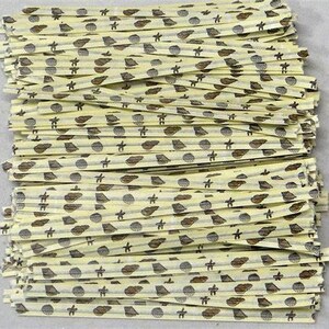 Könnte beinhalten: Ein Stapel dünner, gelber Papierstrohhalme mit einem braunen und weißen Muster aus Muscheln und Seesternen.