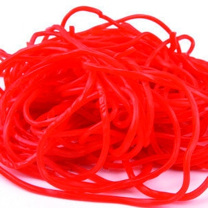 May include: A large pile of bright red licorice twists. The licorice is long and thin, and it is twisted into a variety of shapes.