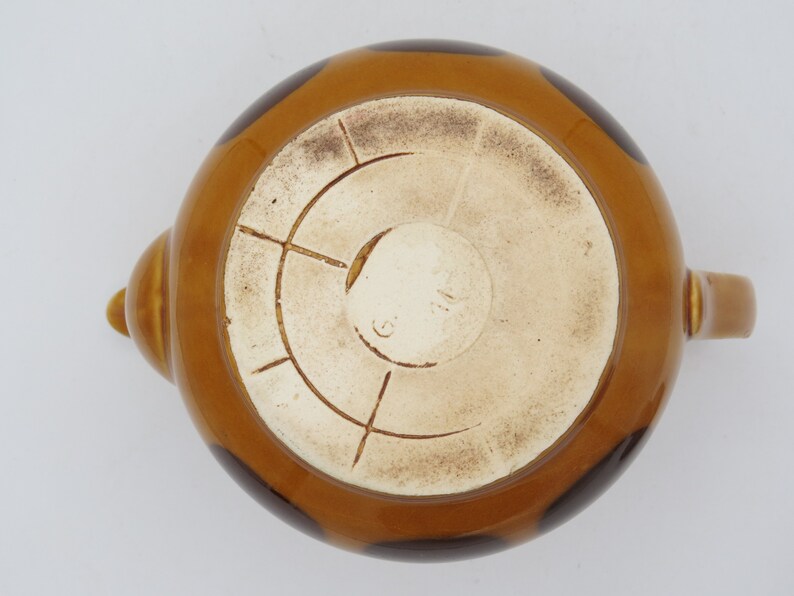 May include: Brown teapot with black polka dots and a white interior. The bottom of the teapot has a circular mark with a number inside.