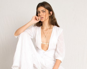 White sheer jumpsuit with sleeves and an open V neckline