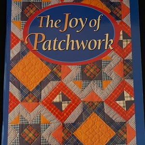 May include: A book titled "The Joy of Patchwork: A Treasury of Patterns and Projects" by Better Homes and Gardens. The cover features a colourful patchwork quilt design with red, orange, blue and yellow squares and triangles.