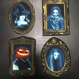 May include: Four ornate gold frames with black backgrounds, each containing a different spooky image. The top left frame shows a woman in a witch's hat, the top right frame shows a girl with a ghostly appearance, the bottom left frame shows a jack-o-lantern, and the bottom right frame shows a woman with a ghostly appearance.