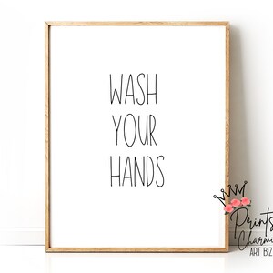 May include: A framed print with the text "Wash Your Hands" in black script font on a white background. The frame is a light brown wood.
