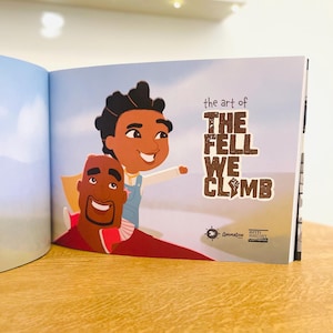 May include: An open book with an illustration of a father and son on a blue sky background. The book title is "The Art of The Fell We Climb".