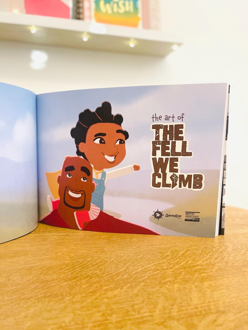 May include: An open book with an illustration of a father and son on a blue sky background. The book title is "The Art of The Fell We Climb".