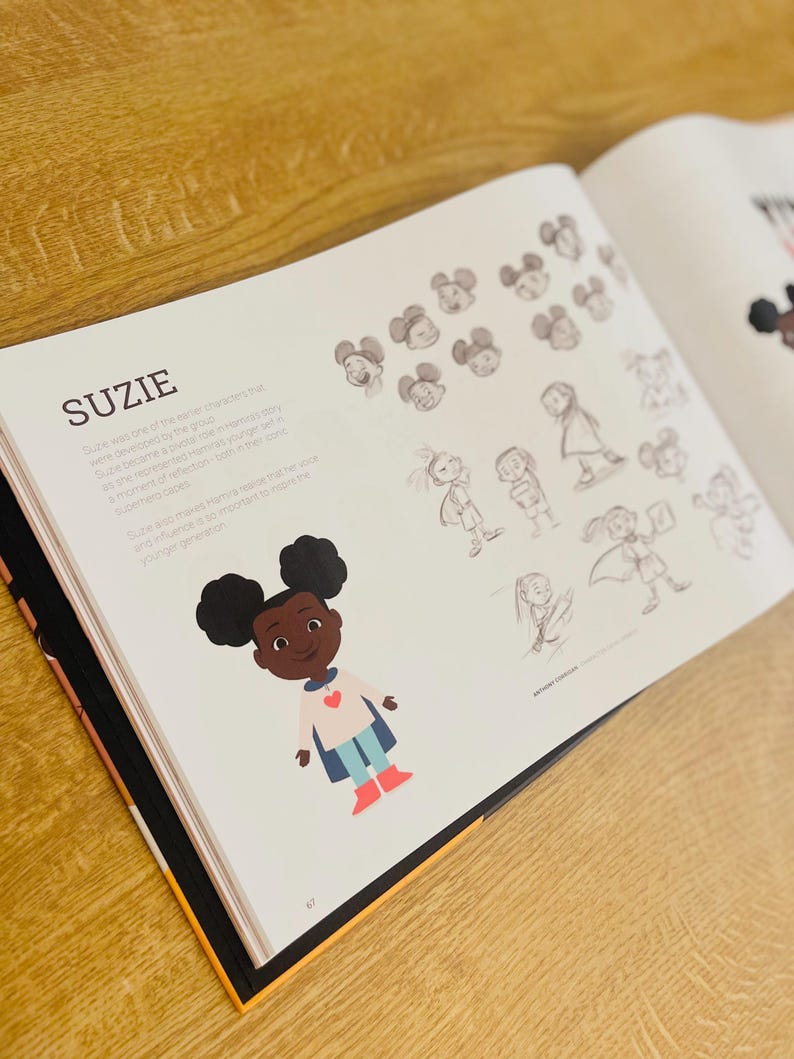 May include: Illustration of a young girl with brown skin and curly black hair wearing a blue cape and red boots. She is smiling and has a red heart on her shirt. The text "Suzie" is written in black above the illustration.
