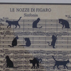 May include: A black and white image of sheet music with the title "Le Nozze di Figaro" and the subtitle "Sinfonia". The music is filled with black silhouettes of cats in various poses.