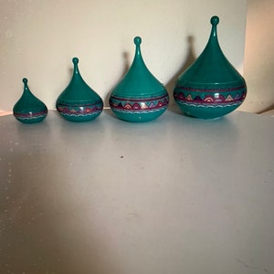 May include: Four teal blue ceramic decorative spinning tops with geometric patterns in shades of purple, pink, and white.