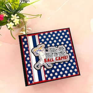 May include: Square baseball-themed card with a blue background covered in white baseballs. The card has a red border and a white and blue striped accent. A baseball player graphic and the text "Take Me Out to the BALL GAME!" are featured on the front.