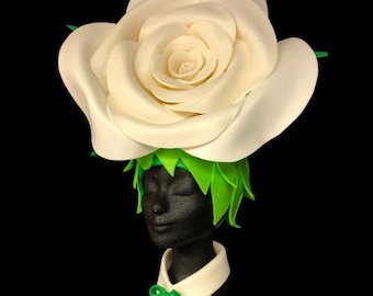 May include: A white foam rose headwear with green foam leaves. The rose is large and has many layers of petals.