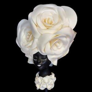 May include: A black and white sculpture of a person wearing a large white flower crown. The sculpture is made of a smooth, matt material.