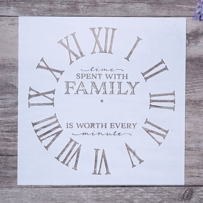 May include: White stencil with a clock face design. The clock face has Roman numerals and the text "time spent with family is worth every minute".