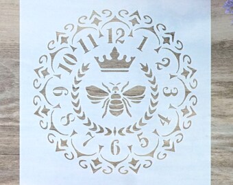 Op de afbeelding: Witte sjabloon met een decoratief ontwerp met een bij, een kroon en Romeinse cijfers rond de rand. De sjabloon is voor knutselen en decoreren.