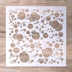 May include: White stencil featuring a design of circles of varying sizes, some overlapping, creating a bubble-like pattern.
