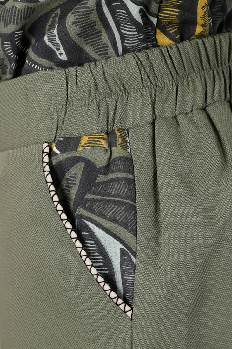May include: Green pants with a black and white patterned pocket. The pocket has a white trim.