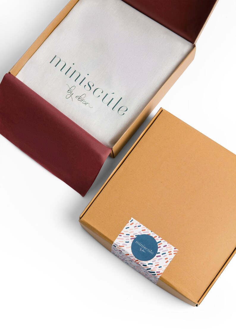 May include: Two cardboard boxes with the logo "miniscule by obrar" printed on them. The top box is open and has a red tissue paper lining. The bottom box is closed and has a colorful sticker with the same logo on it.