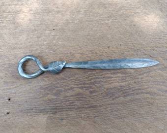 May include: A silver metal letter opener with a leaf design on the handle and a twisted loop.