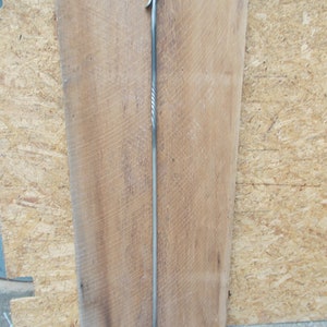 May include: A long, silver metal fireplace poker with a twisted handle and a hook at the end.