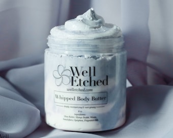 May include: A white whipped body butter in a clear jar with a black label that says "Well Etched" and "Whipped Body Butter - deeply moisturizing & non-greasy - 8 oz. Ingredients: Shea Butter, Mango Butter, Water, Emulsifiers, Optiphen, Fragrance Oil".