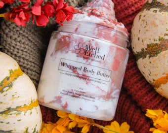 May include: A jar of whipped body butter with a white and pink swirl design, surrounded by pumpkins and flowers. The jar has a label that reads "Whipped Body Butter" and "deeply moisturizing & non-greasy". The jar is 8 oz.