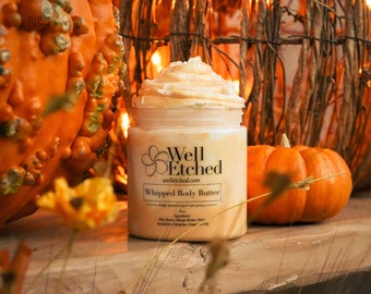 Può includere: Un barattolo di burro corporeo montato con un profumo di zucca e spezie. Il barattolo è etichettato "Well Etched" e "Whipped Body Butter". Il barattolo è appoggiato su una superficie di legno con zucche sullo sfondo.