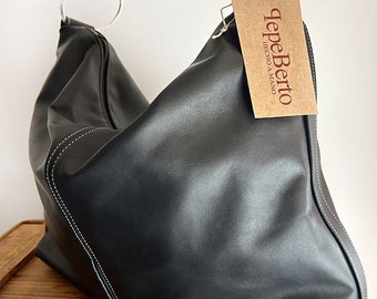 Women's black cowhide bag with handle at shoulder height. Zipper closure and large capacity.