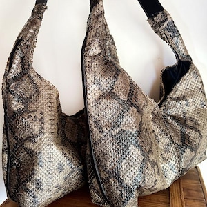 Pode incluir: Duas bolsas de mão de pele de cobra castanho com alças pretas. As bolsas de mão são feitas de um material texturizado e têm um design descontraído.